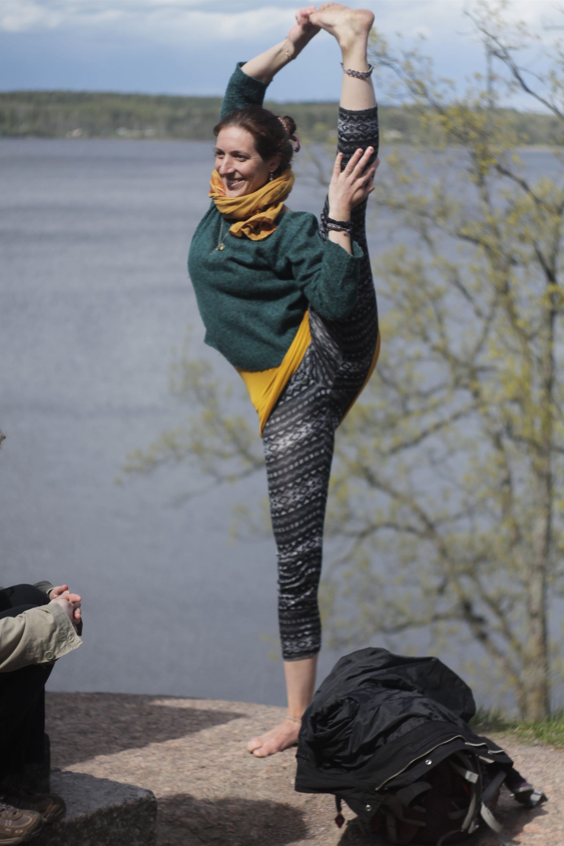 Christina Weis in a standing-splits yoga pose beside a lake