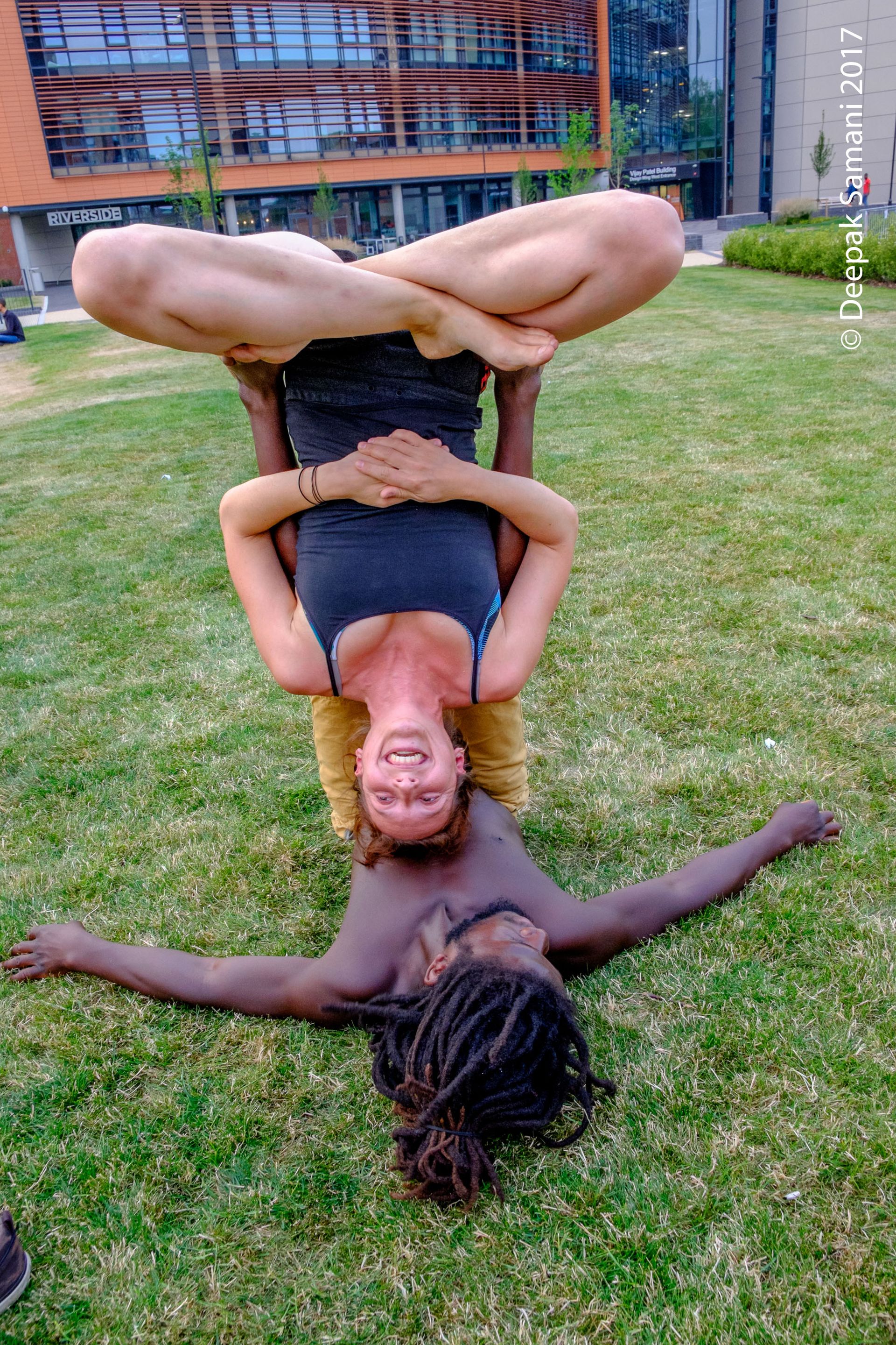 Two people practising AcroYoga outside the DMU Riverside building