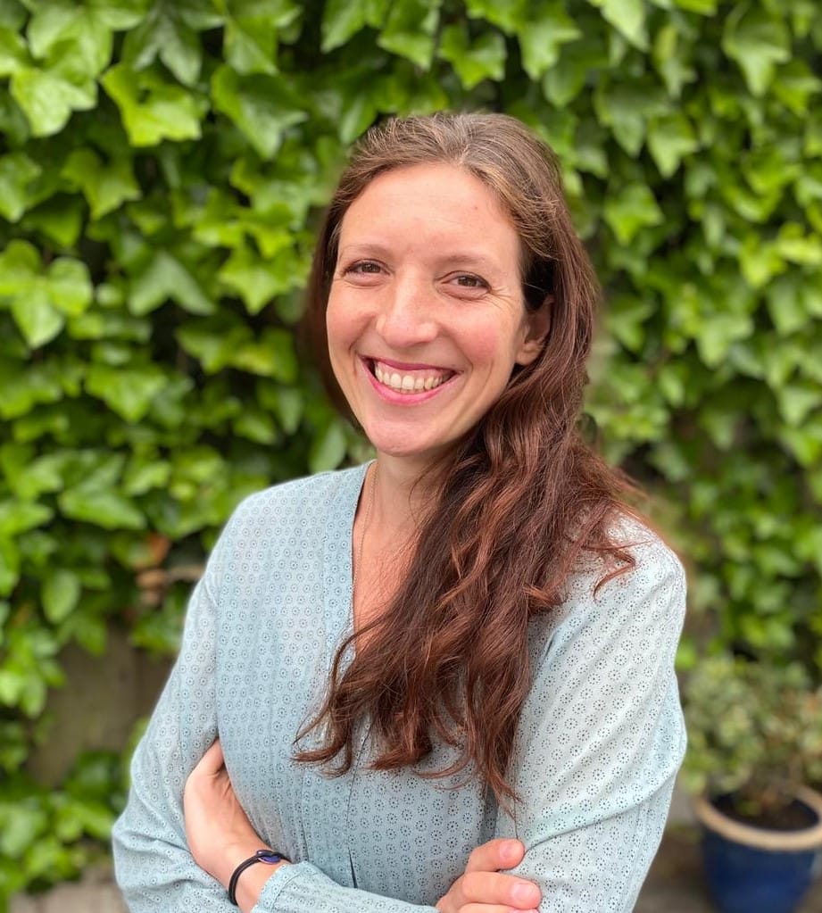 Christina Weis smiling in front of an ivy-covered wall